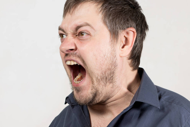 Wściekły agresywny mężczyzna krzyczy z otwartymi ustami. Ludzki płacz nad dzieckiem albo kłótnia w rodzinie. Gniew i negatywne emocje z krzykiem. - Zdjęcie, obraz