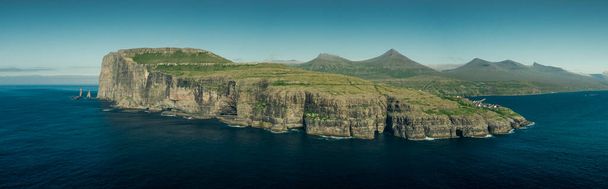 Панорамный вид на побережье острова Эйстурой с горными породами Ризин-ог-Келлингин на Фарерских островах в течение дня с солнцем и голубым небом, голубым океаном и зелеными скалами - Фото, изображение