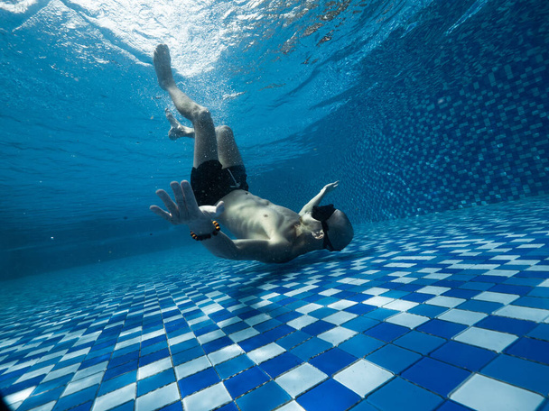 A young Caucasian man in snorkel mask and short underneath the swimming pool - Foto, Imagem