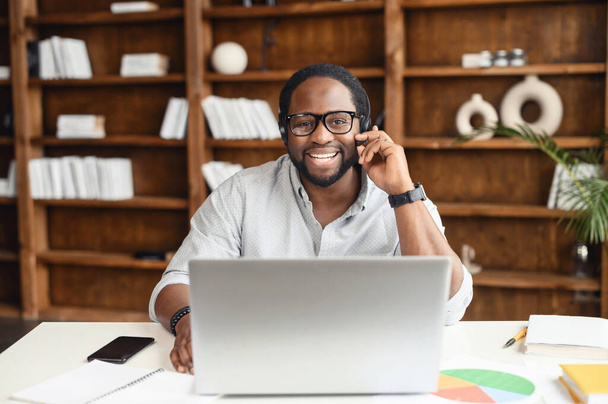 Jonge zakenman met een bril met een headset op kantoor - Foto, afbeelding