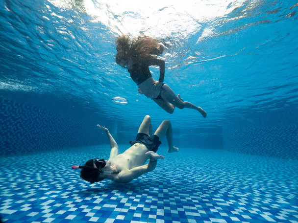 Underwater maternity photoshoot of a young pregnant couple in the swimming pool - Foto, Imagem