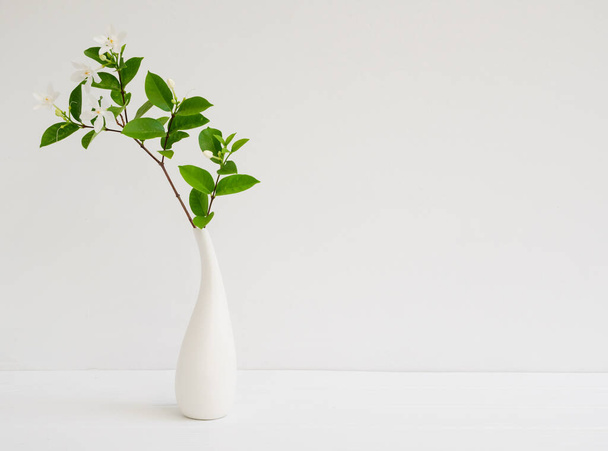 Красивая маленькая белая Gardenia цветы в современной вазе установлен на деревянный стол стены фона с копировальным пространством, мягкий тон натюрморта - Фото, изображение