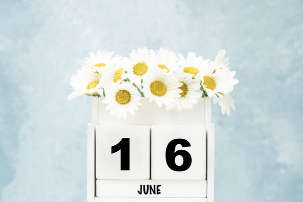Calendario bianco cubo per giugno con fiori margherita su sfondo blu con spazio copia - Foto, immagini