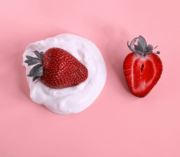 Tuore luonnollinen jogurtti punaisella viipaloidulla mansikalla vaaleanpunaisella taustalla. Kreikkalainen jogurtti ja punainen marja aamiainen käsite. Ruoan minimalismi. Kalsiumin ja proteiinin lähde. Moderni ruoka esteettinen - Valokuva, kuva