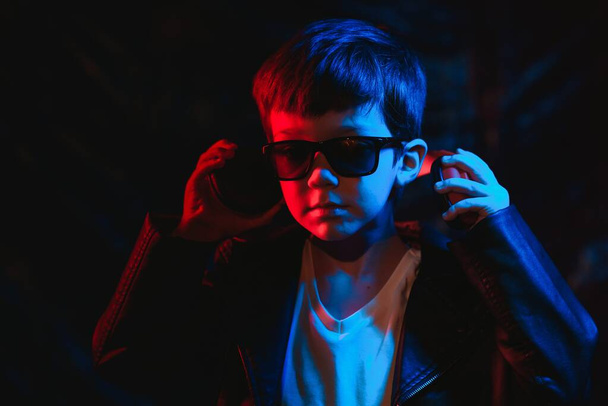 Studio shot in dark studio with neon light. Portrait of a stylish boy with headphones - Foto, afbeelding