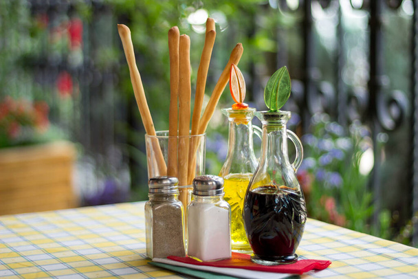Italian serving. Table set of olive oil, bread sticks, salt, pepper, soy sauce, vinegar - Photo, Image
