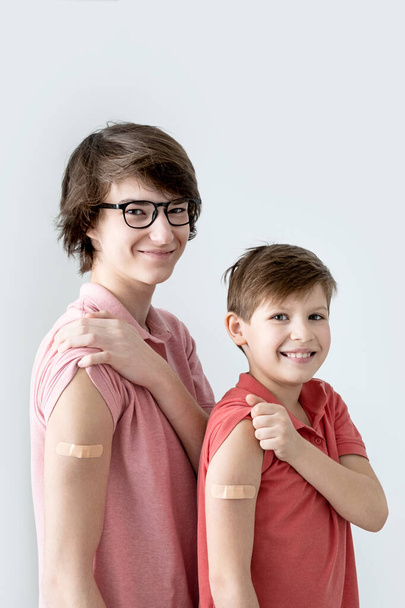 Κάθετα. Νέοι άνδρες, έφηβοι και αγόρι εμβολιάστηκαν κατά της λοίμωξης από τον ιό του στομίου. Εμβολιασμός κατά του covid-19. - Φωτογραφία, εικόνα