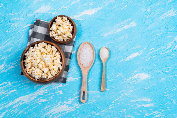 Kommen popcorn kleine en grote porties op een blauwe achtergrond. Het concept van vrije tijd en entertainment. kopieerruimte - Foto, afbeelding