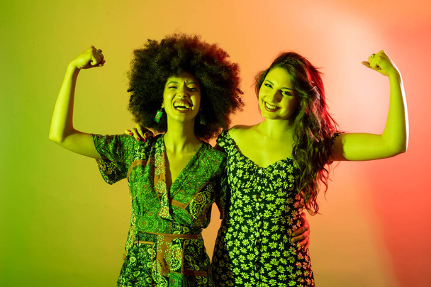 Молоді багатоетнічні жінки ізольовані усміхнені показують біцепси
  - Фото, зображення