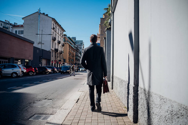 Rückansicht junger kaukasischer Geschäftsmann zu Fuß im Freien mit Aktentasche  - Foto, Bild