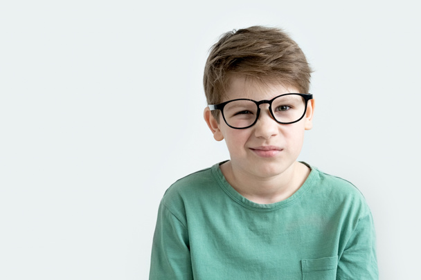 Surprised boy in a green T-shirt and glasses. Copy space. Sad child. Unhappy teen - Photo, Image