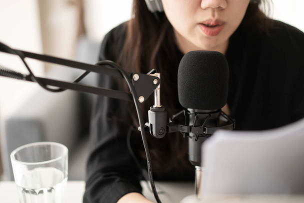 Hermosa y atractiva joven mujer asiática que arregla el canal de podcast en casa. Mujer de negocios grabando su podcast para su podcast en línea en vivo en la computadora portátil y la tableta. Estilo de vida laboral moderno - Foto, Imagen