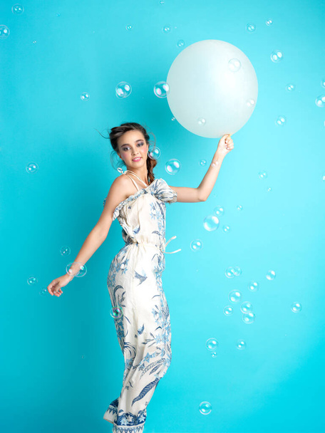piękna, szczęśliwa, młoda kobieta skacząca z nadmuchiwanym balonem w ręku, otoczona balonami z mydłem. - Zdjęcie, obraz