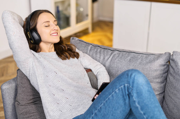 Young woman wearing headphones enjoys favorite tracks - Photo, image