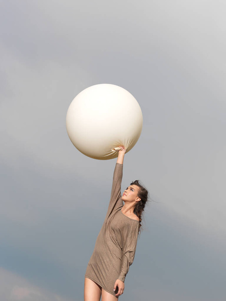 glückliche, junge Frau springt mit großem, weißem Ballon - Foto, Bild