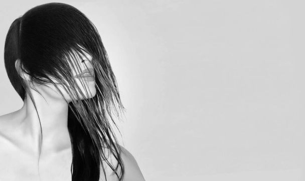 Hair styling concept. Monochrome beautiful young woman with long black hair brushed forward in a modern wispy style covering her eyes on a grey background with copyspace - Фото, изображение