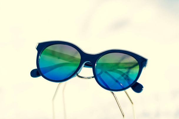 Fashion kattenoog zonnebril model voor dames met grote ronde gekleurde lenzen en zwarte frame shoot buiten in een zonnige dag close-up. Selectieve focus  - Foto, afbeelding