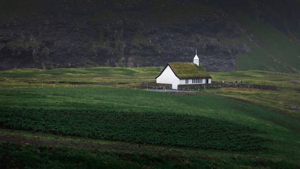Kerk in Saksun Bay op Streymoy Island, donkere regenwolken in de lucht, Faeröer eilanden - Foto, afbeelding