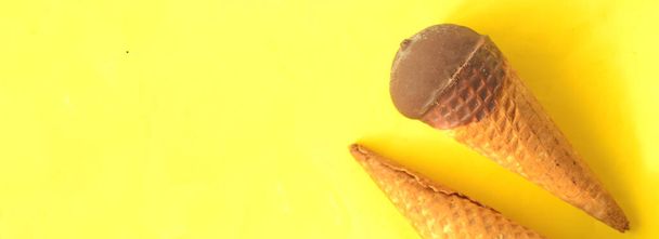 Chocolate ice-cream cone on sunny summer yellow background. - Φωτογραφία, εικόνα