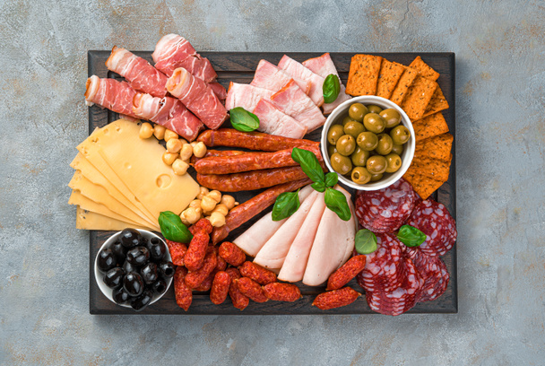 Meat appetizer, cheese and olives on a rectangular cutting board. Top view, horizontal. - Foto, Imagen