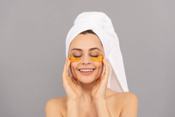 szczęśliwa pani z ręcznikiem frotte używać twarzy złote oko przepaski na skórę, spa. - Zdjęcie, obraz