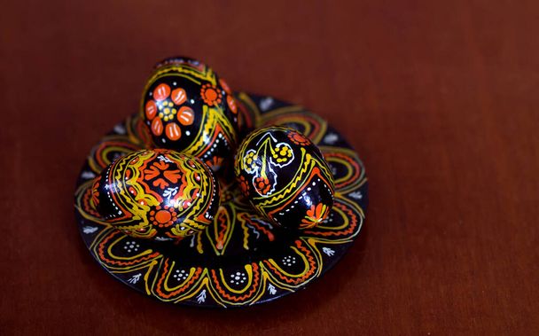 Mischung gefärbter Ostereier mit den traditionellen slawischen Mustern der Ukraine. Schöne pysanka handgemachte ukrainische traditionelle auf einem Teller auf braunem Holzhintergrund. Selektiver Fokus - Foto, Bild