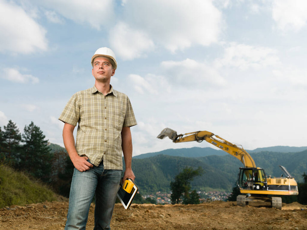 caucasian engineer standing on construction site holding digital tablet and measurement device - Fotografie, Obrázek