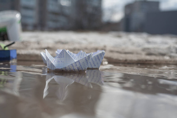 a white boat from a notebook sheet floats on a spring puddle - Фото, зображення