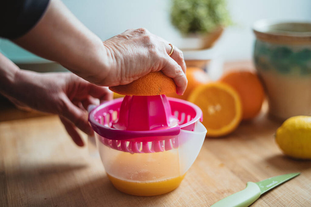 Жінка стискає апельсин, щоб зробити апельсиновий сік вранці (вид збоку
). - Фото, зображення