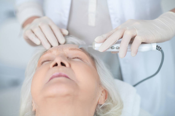 Mujer madura teniendo tratamiento de belleza facial en una clínica de belleza - Foto, Imagen