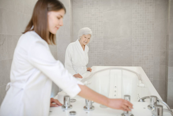 Specialist in spa salon getting the bath for hydromassage ready - 写真・画像