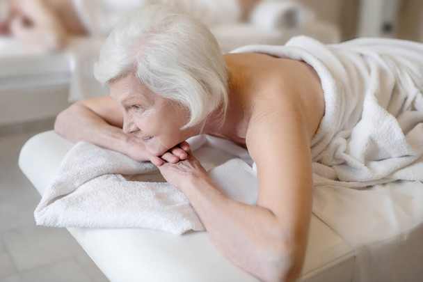 Senior woman lying on na couch in a spa salon - Foto, imagen