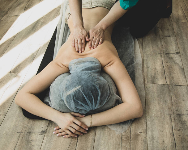Mujer irreconocible teniendo masaje shiatsu por profesional en piso de madera en el hotel - Foto, Imagen