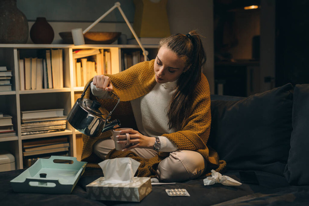 молода жінка має грип. вона вдома п'є чай
 - Фото, зображення