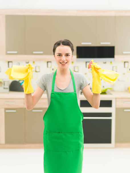 ritratto di felice donna caucasica in piedi in cucina e in possesso di prodotti per la pulizia - Foto, immagini