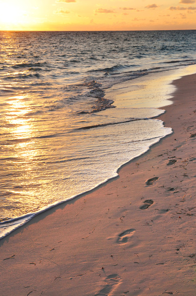lábnyomok, napkelte homokos tengerparton - Fotó, kép
