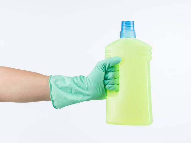 mano humana que usa un guante de goma protector, sosteniendo una botella de plástico con detergente de limpieza líquido sobre fondo blanco - Foto, Imagen