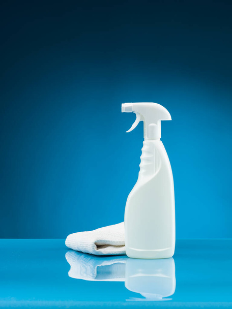 καθαρίζοντας μπουκάλι σπρέι και κουρέλι σε μπλε φόντο - Φωτογραφία, εικόνα