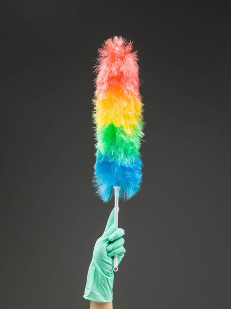 hand holding up synthetic feather duster against grey background - Photo, Image