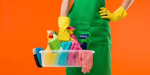 primer plano de la señora de la limpieza que sostiene suministros, sobre fondo naranja - Foto, Imagen