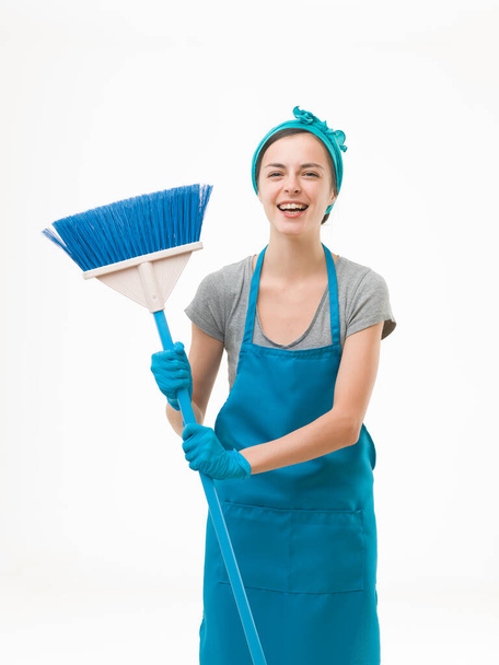 幸せな掃除の女性が立って、ほうきを持って笑っている。白い背景に隔離され - 写真・画像