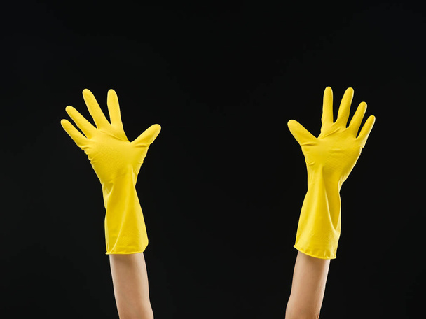 hands up with yellow rubber gloves with open palms on black background - Photo, image