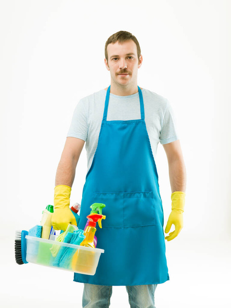 caucasian janitor wearing apron and holding basin with cleaning supplies, on white background - Valokuva, kuva