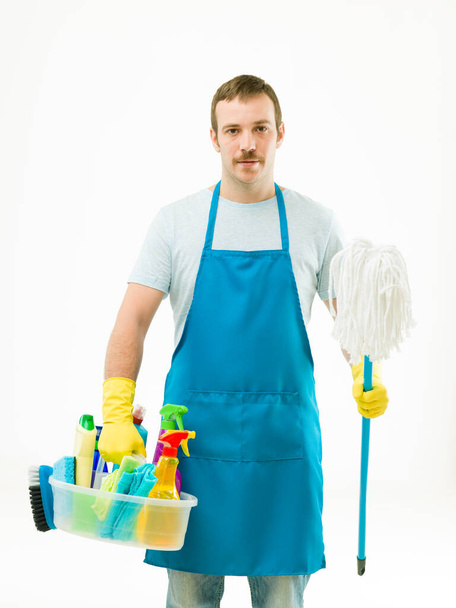 красивый мужчина держит чистящие средства и швабру, на белом фоне - Фото, изображение