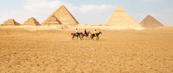 Blick auf die großen ägyptischen Pyramiden in Gizeh und drei Reiter davor. - Foto, Bild