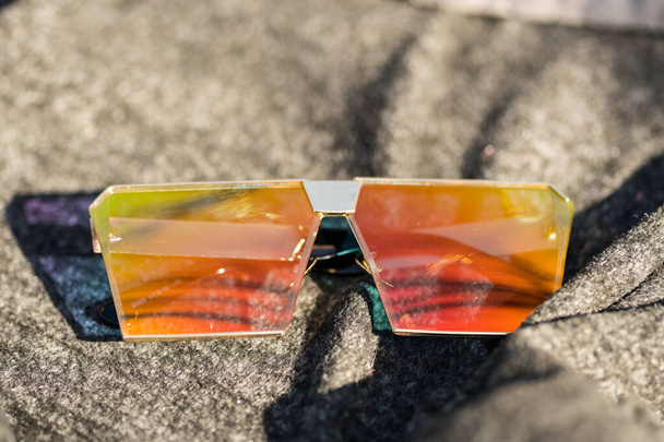 Модель негабаритних сонцезахисних окулярів з великими плоскими лінзами знімається на вулиці в сонячний день крупним планом. Вибірковий фокус
 - Фото, зображення