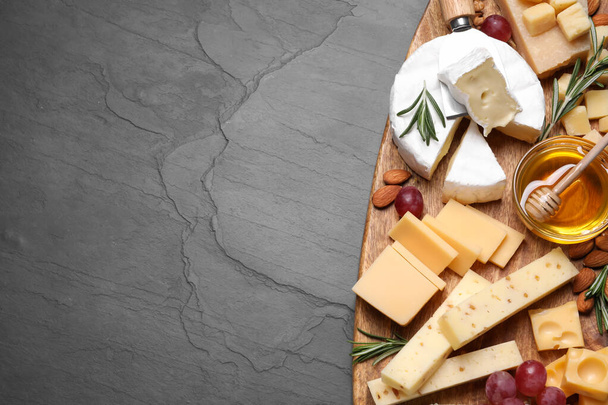 Cheese plate with honey, grapes and nuts on black table, top view. Space for text - 写真・画像