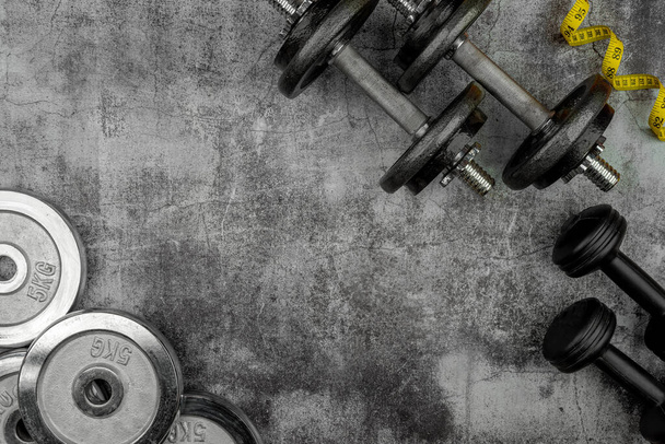 Estilo de vida saudável powerlifting conceito de treino com aderência de ferro fundido placas de peso olímpicas e fita métrica em um piso de cimento. Espaço de cópia vazio - Foto, Imagem