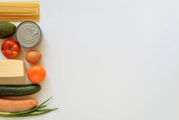 Set of various grocery on the white background, copy space. Food products frame. Spaghetti,canned food, egg, avocado,apple, cucumber, carrot, onion, cheese, tangerine.  - Φωτογραφία, εικόνα