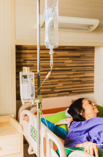 Ανώτερος ασθενής χέρι με ένεση αλατούχο διάλυμα βρίσκεται στο κρεβάτι του νοσοκομείου. - Φωτογραφία, εικόνα